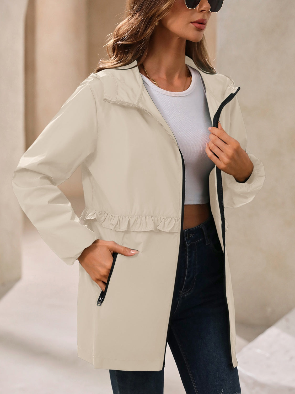 Tan hooded windbreaker jacket with ruffled waistline and zippered pockets.