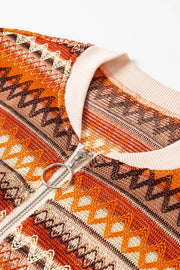 Geometric knit bomber jacket in orange with a silver zipper and cream ribbed collar.