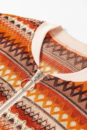 Geometric knit bomber jacket in orange with a silver zipper and cream ribbed collar.