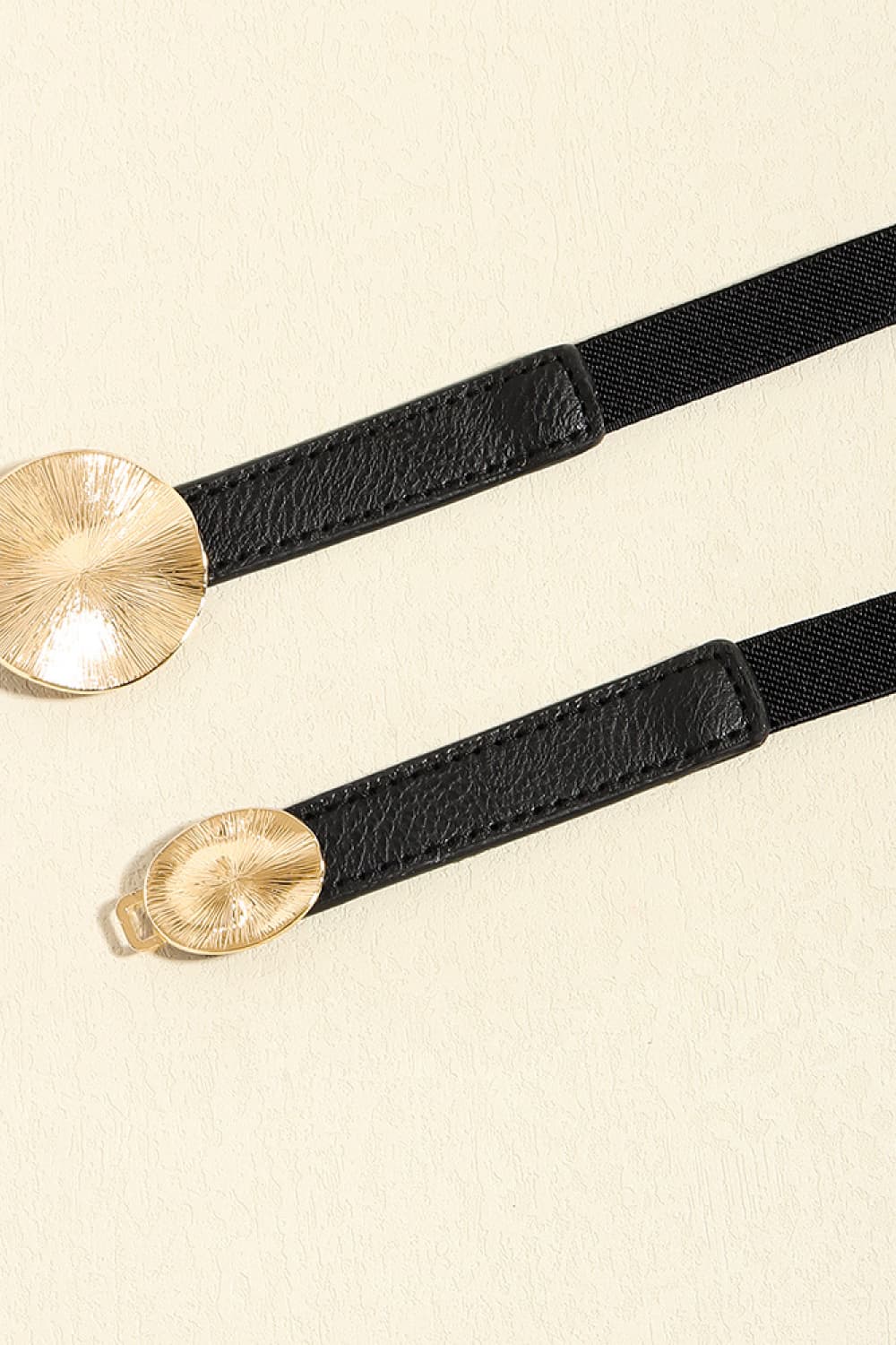 Black elastic belt with faux leather trim and gold disc detail.