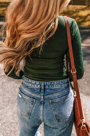 Dark green long sleeve bodysuit with a square neckline, paired with light wash denim jeans.