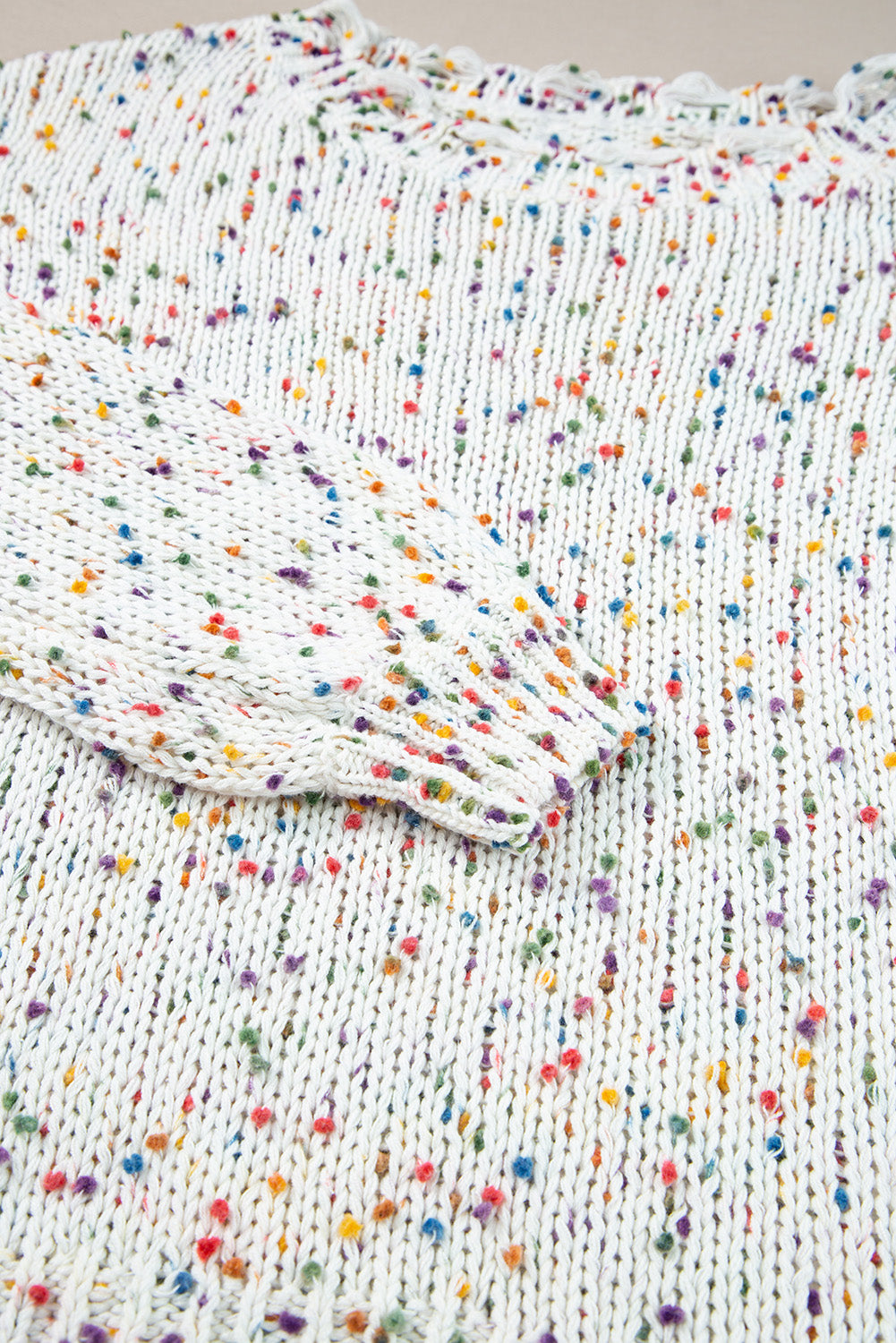 White confetti knit sweater with colorful flecks and distressed hem detail.