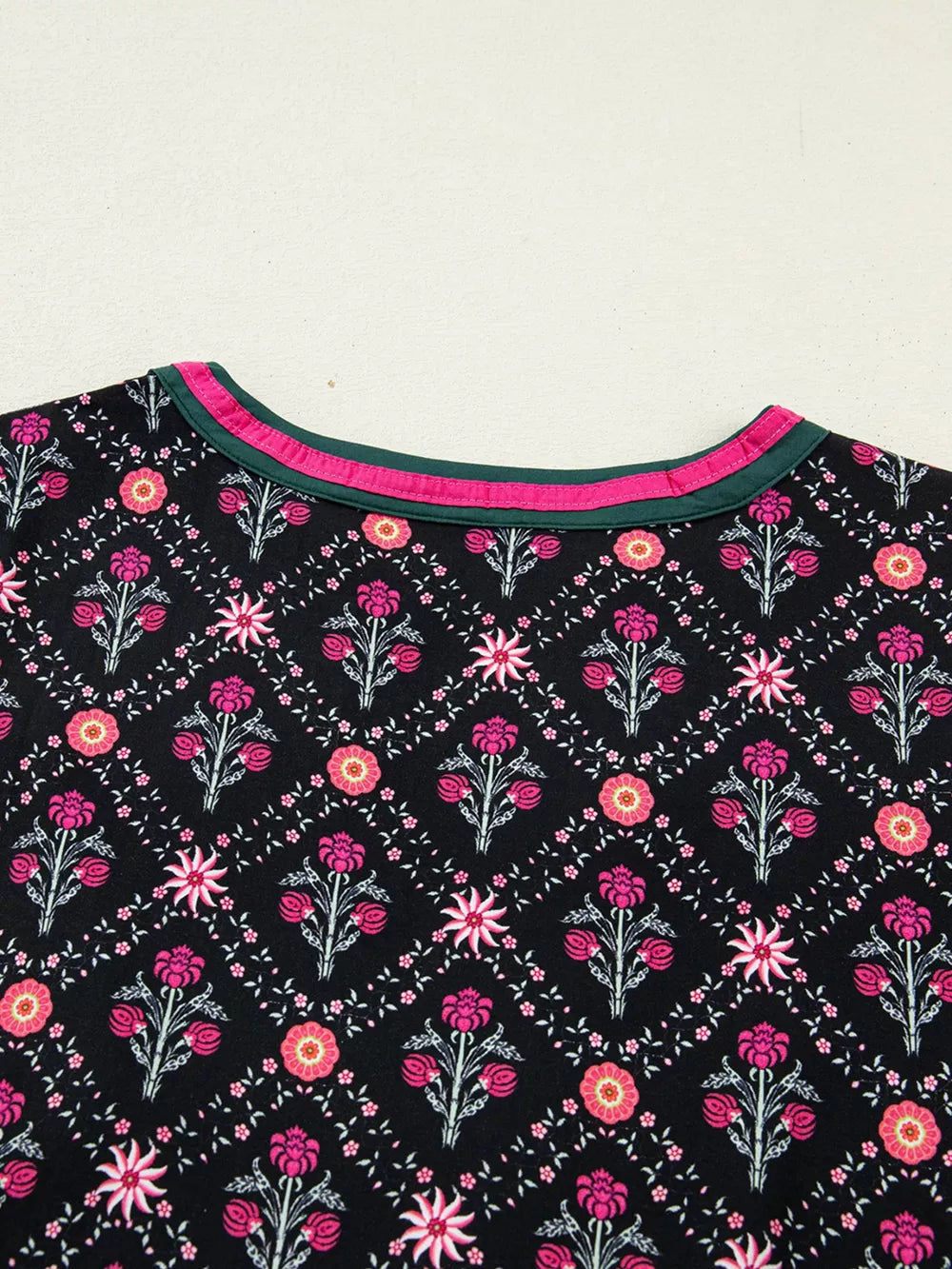 Black cotton blouse with vintage floral pattern and contrast neckline trim.