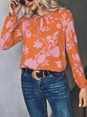 Orange floral tie-neck blouse with pink flowers, long sleeves.