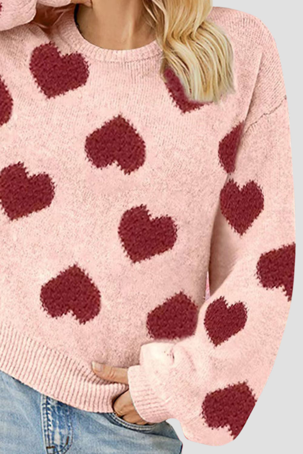 Watermelon pink knit sweater with allover dark red heart motif, balloon sleeves, and crew neck.