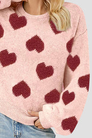 Watermelon pink knit sweater with allover dark red heart motif, balloon sleeves, and crew neck.