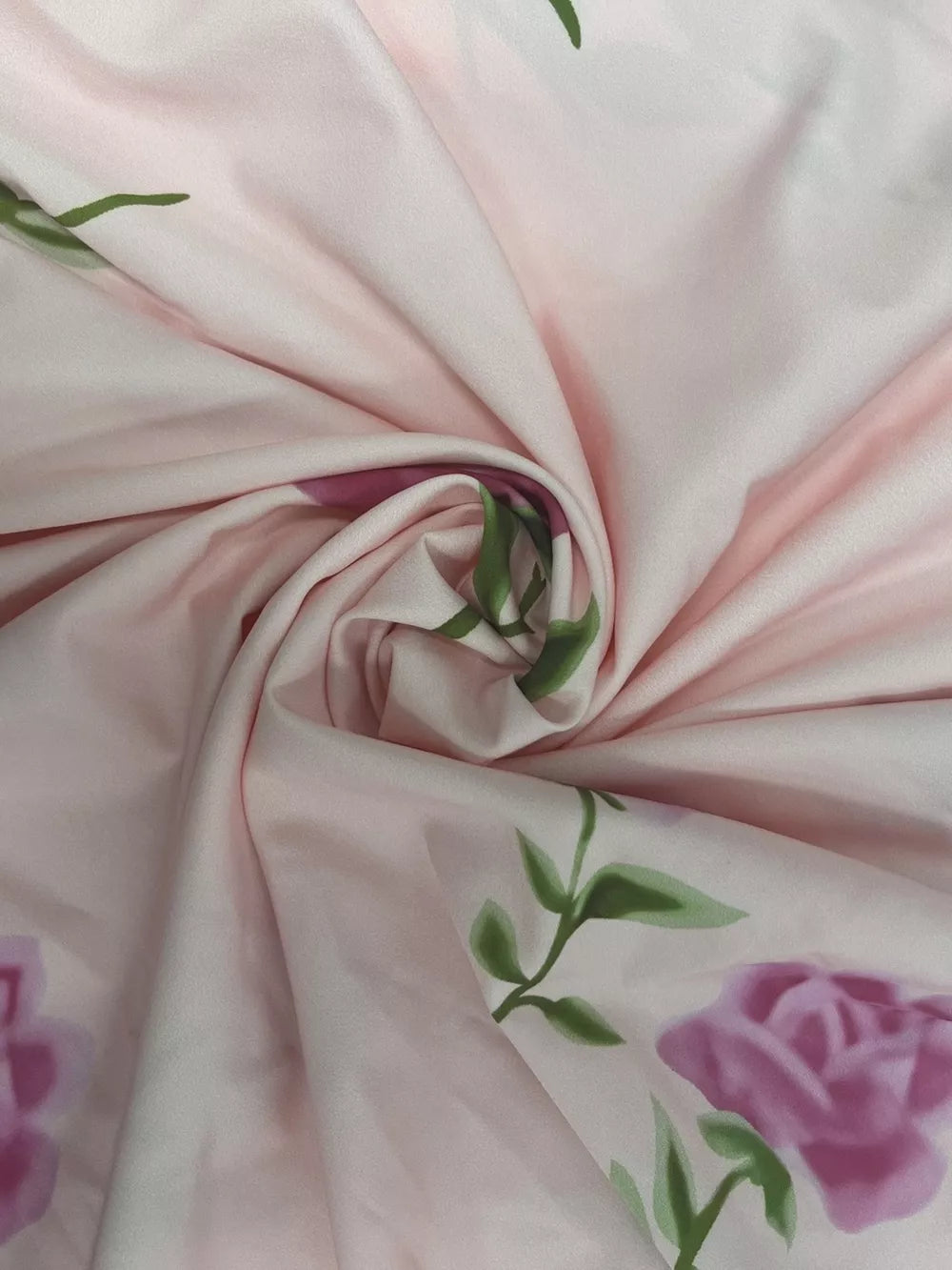 Blush pink floral print maxi dress fabric detail with purple roses and green leaves.