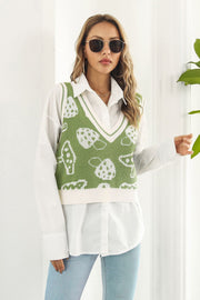 Green knit vest with mushroom motif, V-neck, and cream trim, worn over a white shirt.