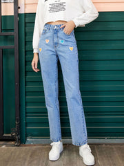 Light wash denim jeans with colorful heart patches and straight leg cut.