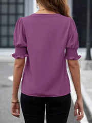 Purple blouse with puffed sleeves and smocked cuffs, V-neck detail.