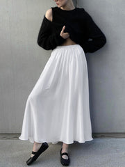 White high-waisted flowy maxi skirt with pockets, styled with a black sweater.