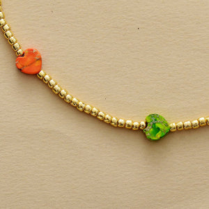 Gold beaded necklace with orange and green heart charms