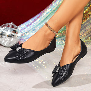 Black pointed toe flats with a dazzling bow detail and a gold anklet.