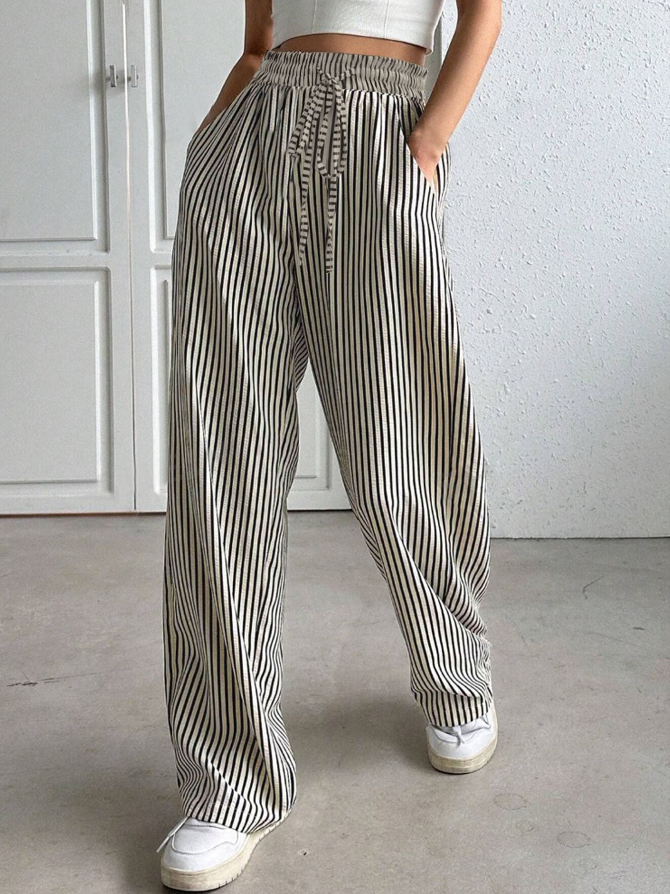 Wide-leg trousers with black and white vertical stripes, drawstring waist, and pockets.