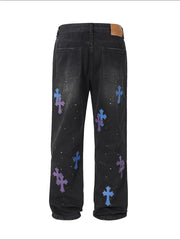 Black denim jeans with embroidered cross patches and paint splatters.