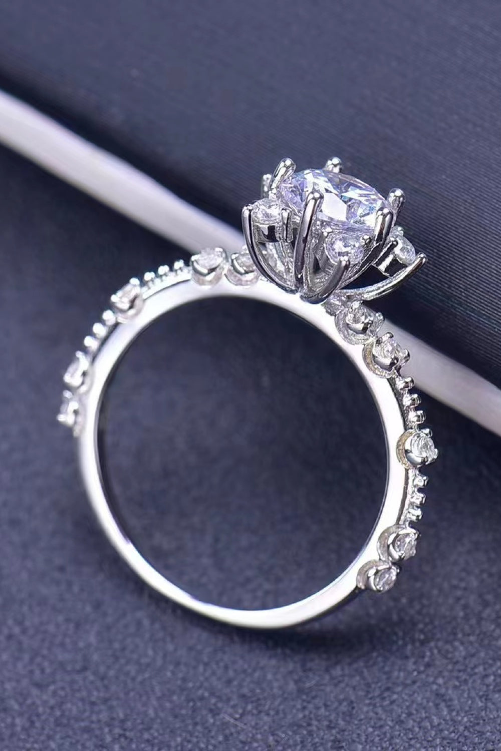 Silver halo ring with floral diamond accents and a central brilliant cut diamond.