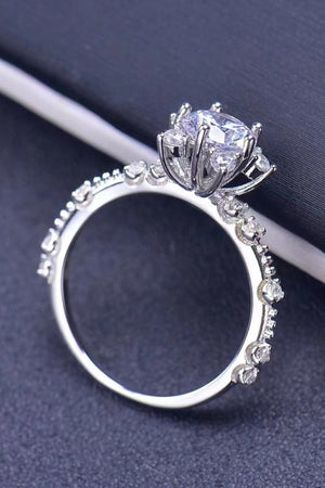 Silver halo ring with floral diamond accents and a central brilliant cut diamond.