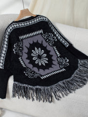 Black acrylic poncho with Aztec motif, fringe hem, and crew neck.