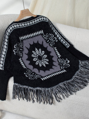 Black acrylic poncho with Aztec motif, fringe hem, and crew neck.