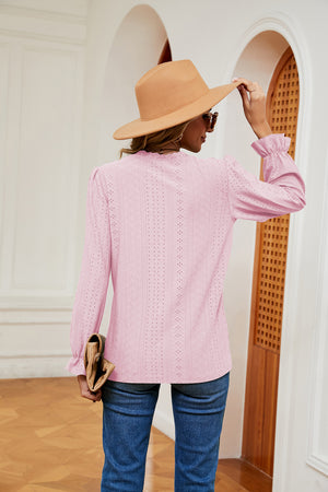 Pink perforated blouse with ruffle cuffs and long sleeves.