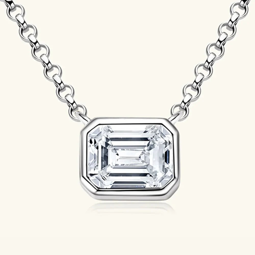 Silver necklace with emerald cut moissanite in gold bezel setting.