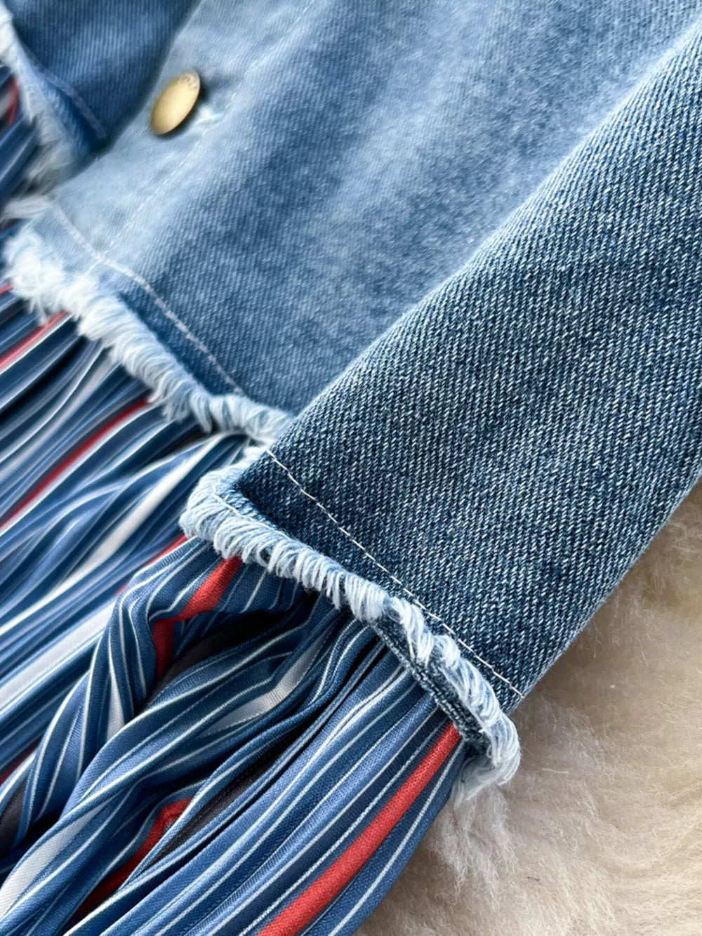 Patchwork denim midi skirt with blue, white, and red striped pleated detail and frayed hem.