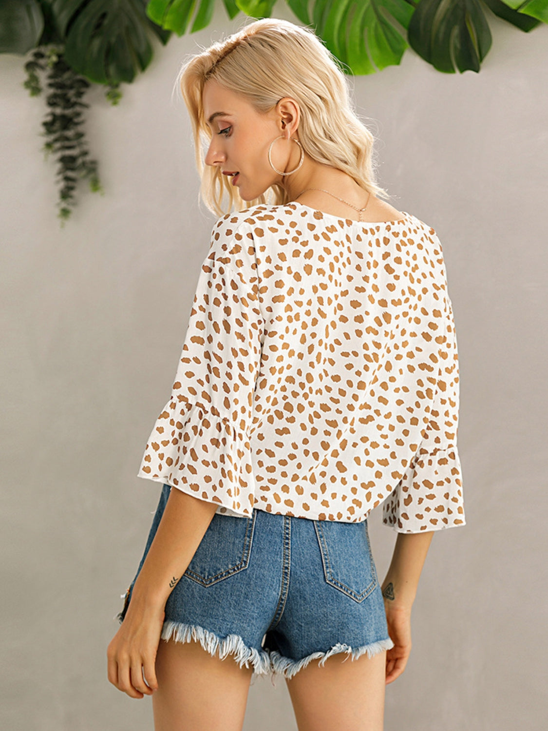 White spotted knot-front blouse with flared sleeves and a square neckline.