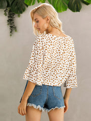 White spotted knot-front blouse with flared sleeves and a square neckline.