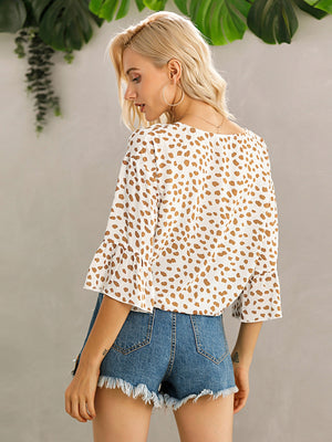 White spotted knot-front blouse with flared sleeves and a square neckline.