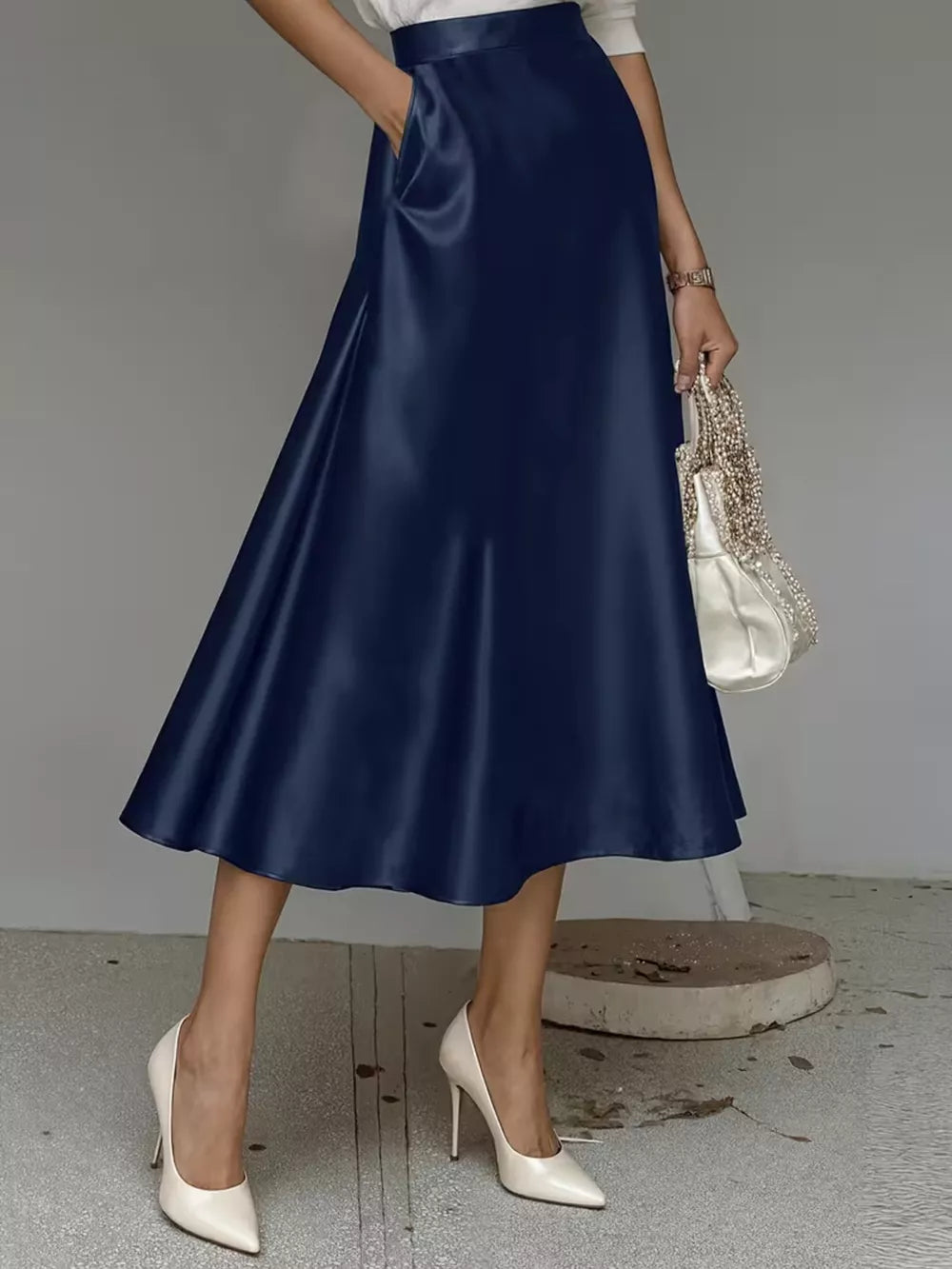 Navy blue A-line satin skirt with pockets, midi length, flowing silhouette.
