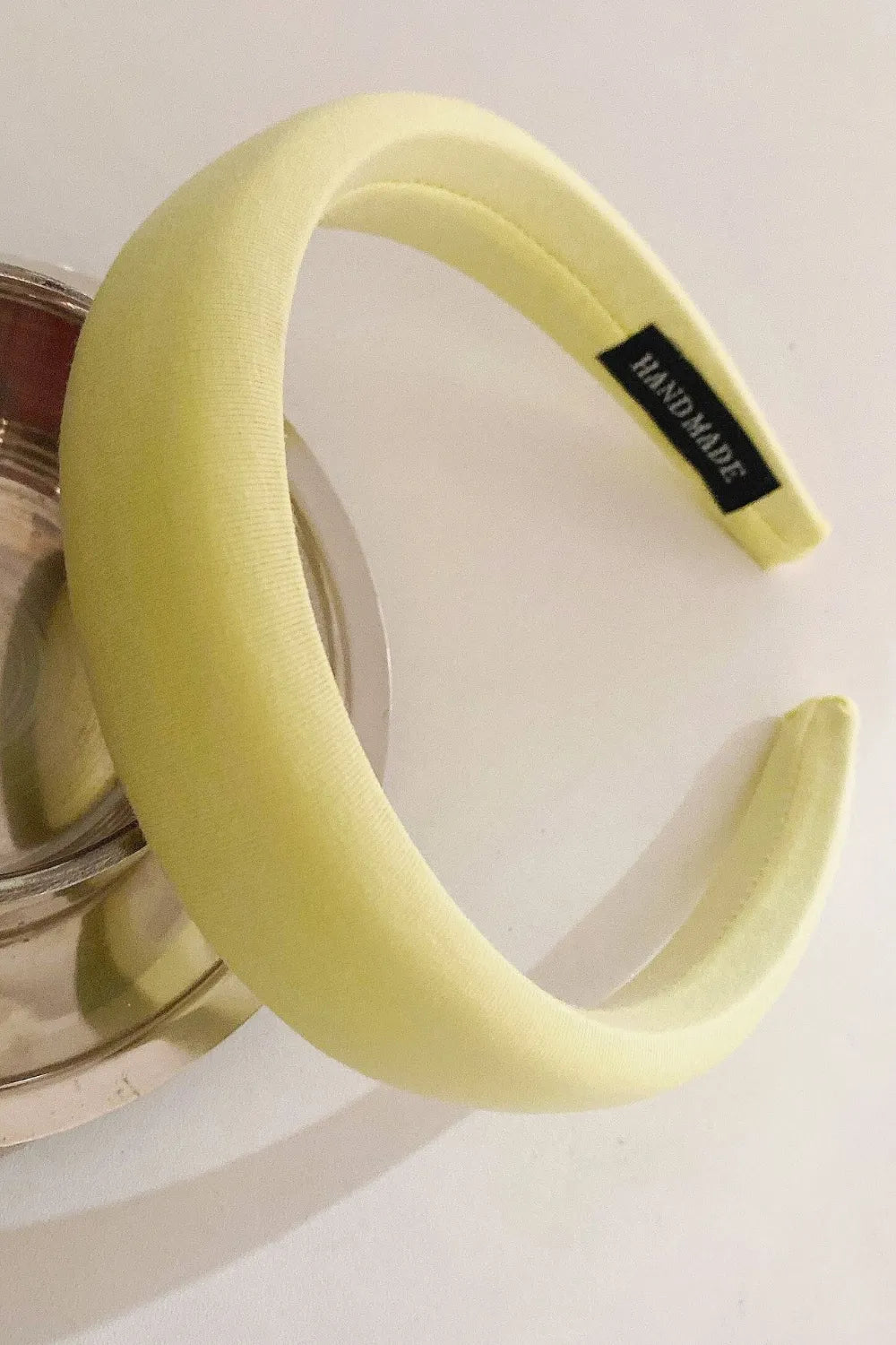 Light Yellow padded headband with textured fabric and a black "HAND MADE" tag.