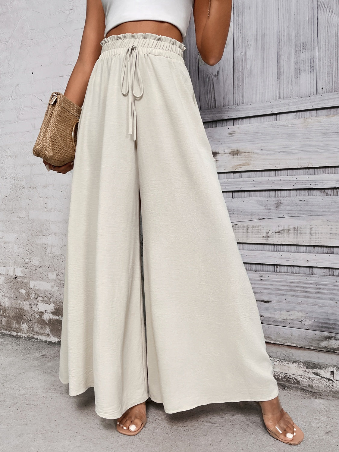 Beige ruffled waistline palazzo trousers with drawstring and wide legs.