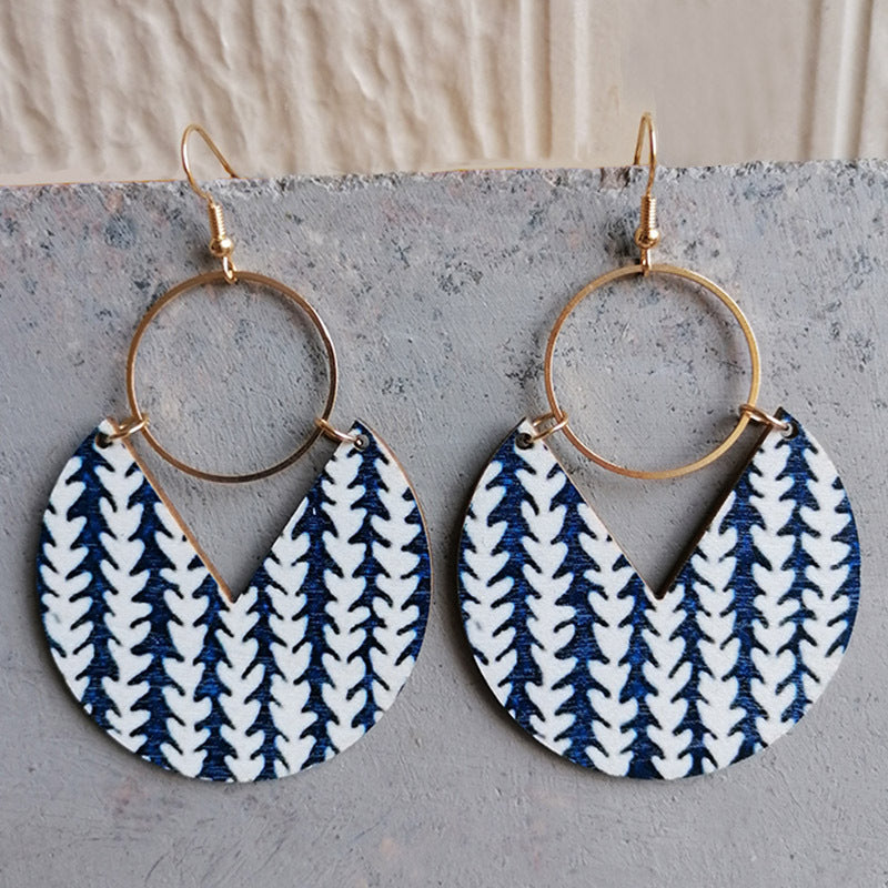 Geometric wood drop earrings with white leaf pattern on blue, gold hoops.