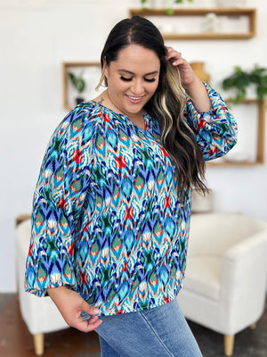 Prismatic ikat blouse in blue with voluminous sleeves and a V-neck.