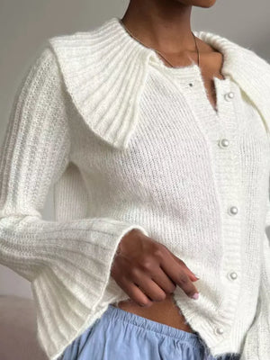 White acrylic cardigan with oversized collar and pearl buttons, ribbed sleeves.