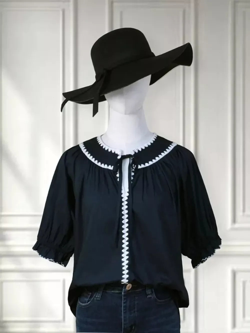 Navy polyester blouse with scalloped white trim and tie-neck, short sleeves.