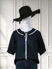 Navy polyester blouse with scalloped white trim and tie-neck, short sleeves.