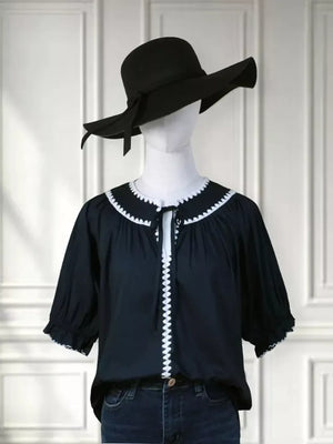 Navy polyester blouse with scalloped white trim and tie-neck, short sleeves.