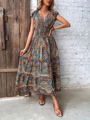 Vibrant tiered maxi dress with smocked bodice, V-neck, short sleeves, and paisley print.