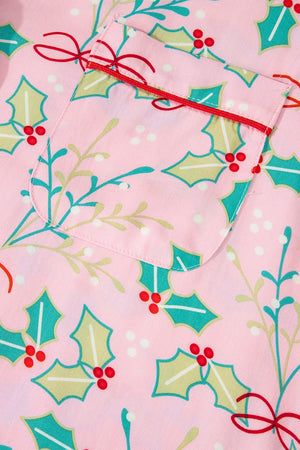 Blush pink pajama set with festive holly print and red trim on pocket.