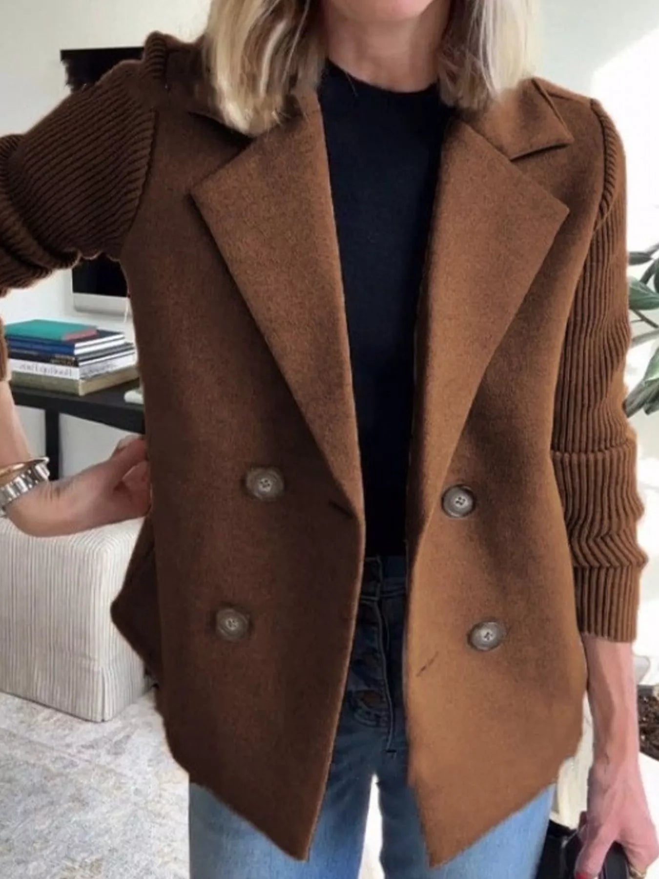 Brown double-breasted trench coat with knit sleeves and button closure.