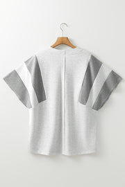 Colorblock waffle knit henley top in gray with striped sleeve details.