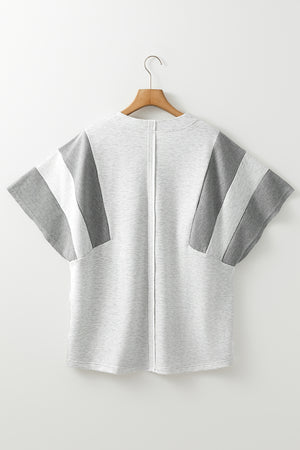 Colorblock waffle knit henley top in gray with striped sleeve details.