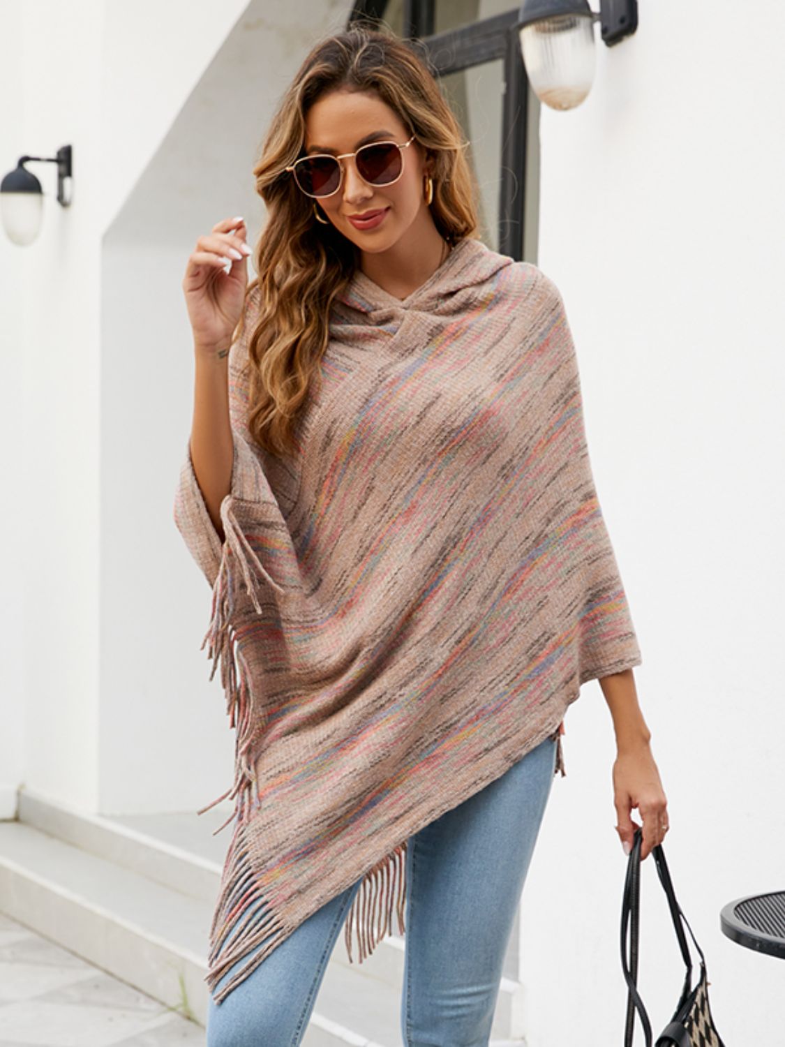 Hooded mélange cape in tan with colorful stripes and fringe detail, worn by a model.