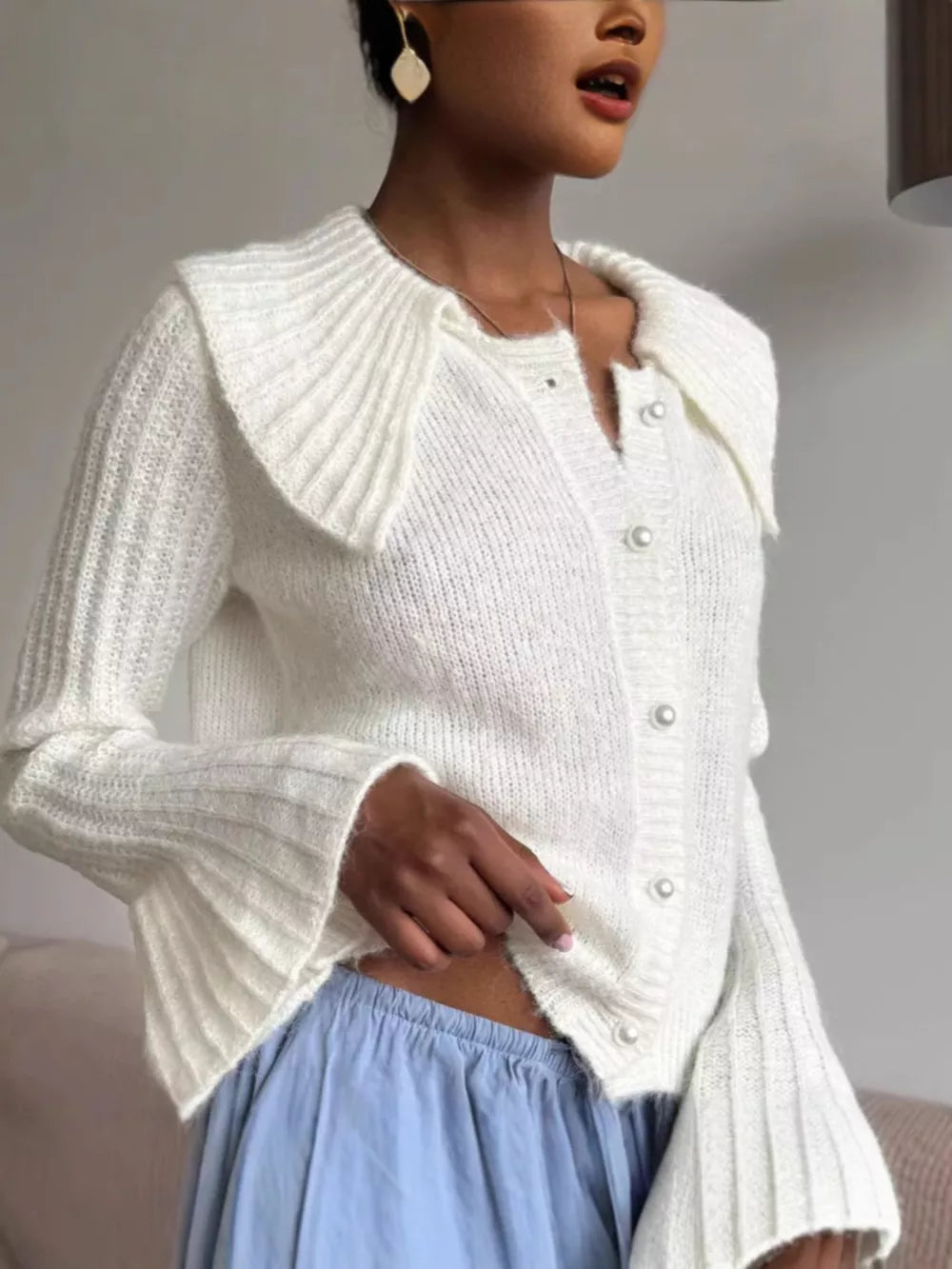 White acrylic cardigan with oversized collar and pearl buttons, bell sleeves.