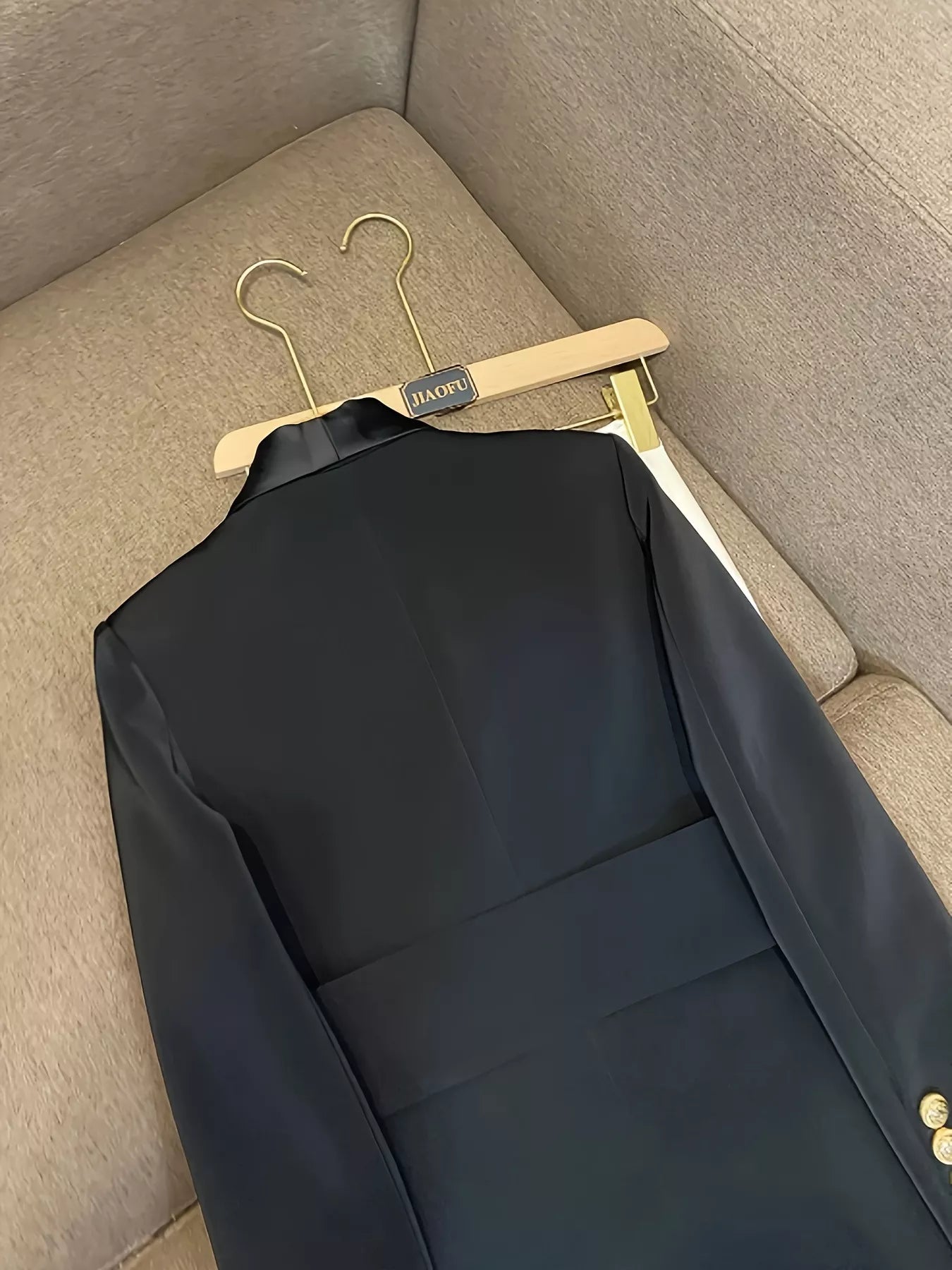 Black double-breasted tailored blazer with satin lapels and gold buttons.