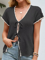 Black tie-front knit cardigan with white trim and short sleeves.