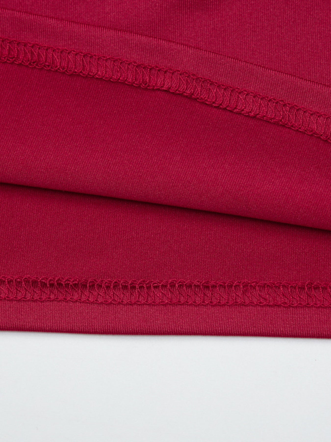 Red fitted one-shoulder t-shirt detail showing fabric texture and stitching.