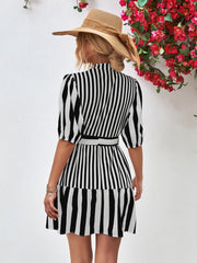Black and white vertical stripe shirred waist dress with puff sleeves and a belted A-line skirt.