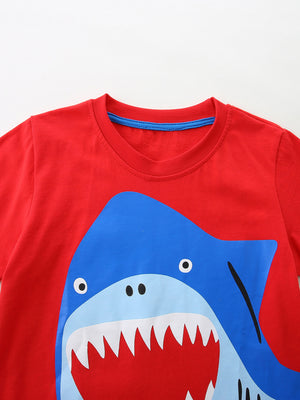 Red cotton toddler t-shirt with a playful blue shark graphic and blue neckline trim.